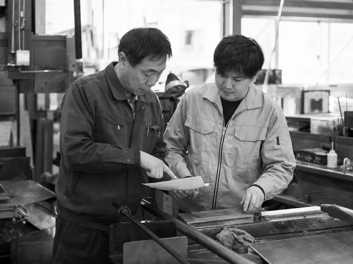 ベテラン社員が若手社員に現場の判断基準を伝えている様子
